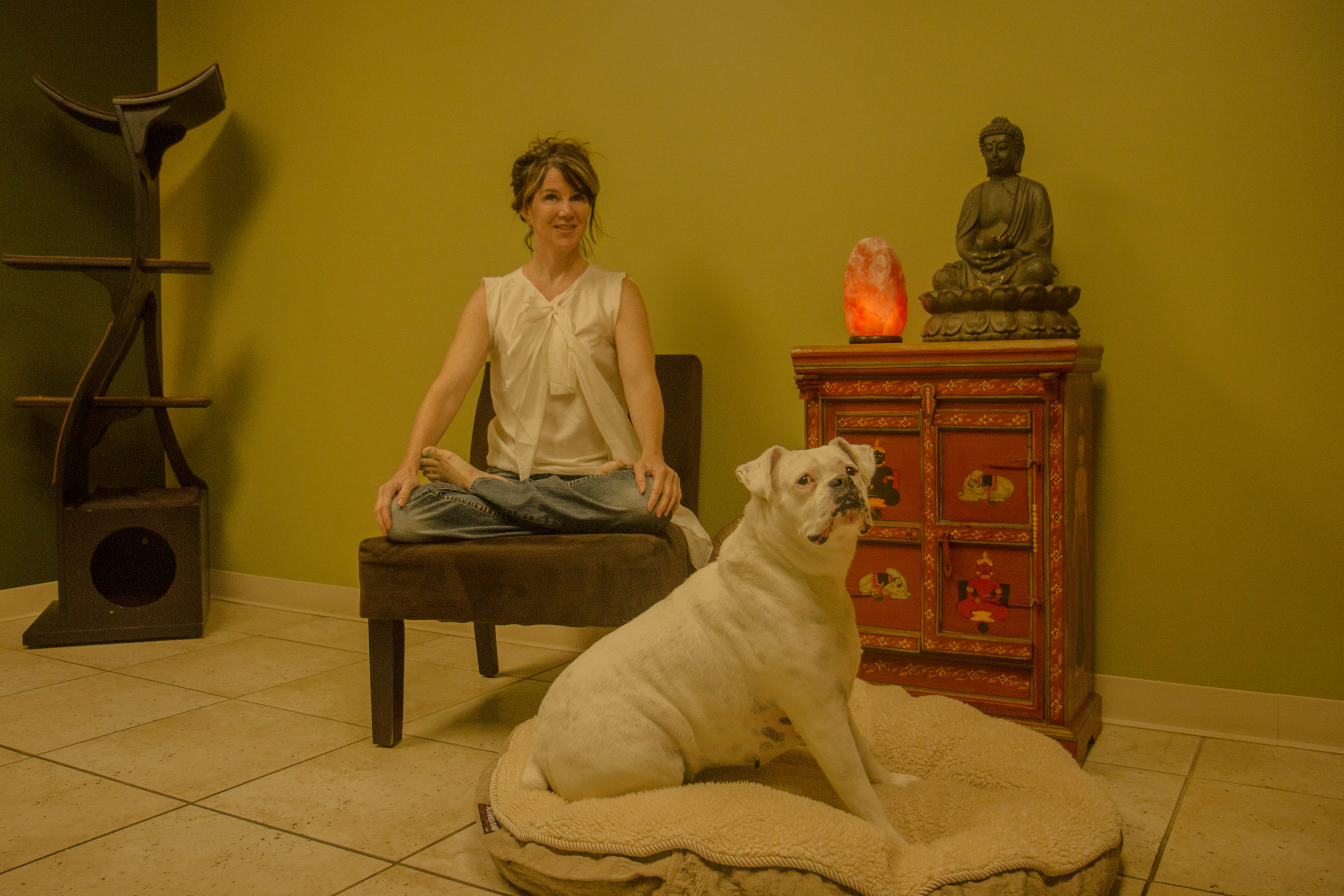 Woman sitting on a chair with a dog in front of her on a pet bed